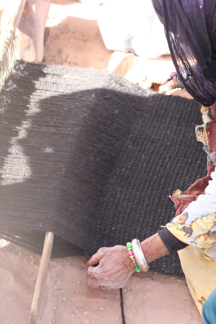 A skilled artisan weaves camel and goat hair on a traditional loom, honoring centuries of craftsmanship as the earthy tones of the fabric emerge.